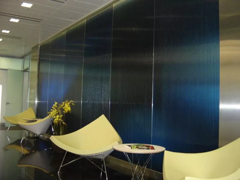 Dark blue reeded glass wall partition in an office lobby with modern lounge seating