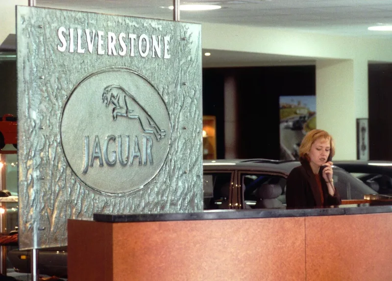 Large textured cast glass logo panel on steel rods behind a showroom reception desk