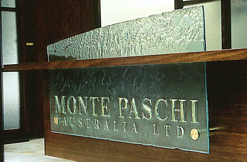 Cast glass name plate with raised lettering and brass fixings on a timber reception desk