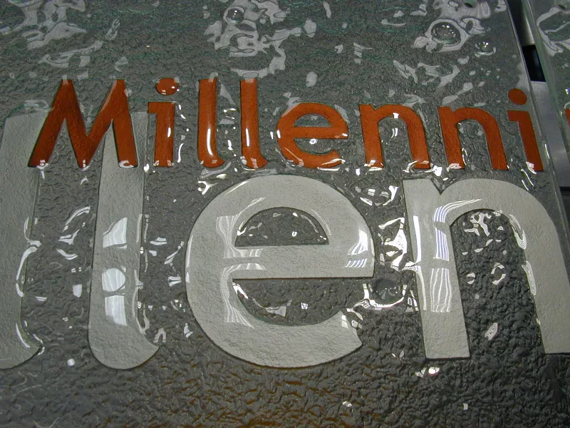 Close-up of a textured cast glass sign panel with raised and coloured lettering