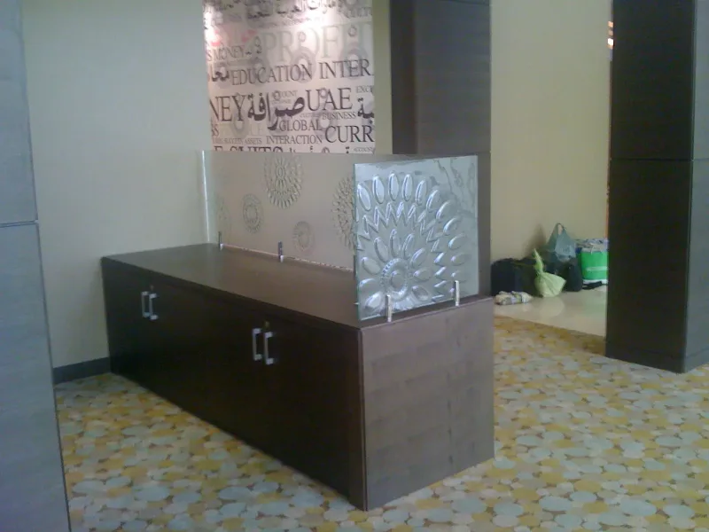 Embossed floral pattern glass screen on stainless standoffs above a reception counter