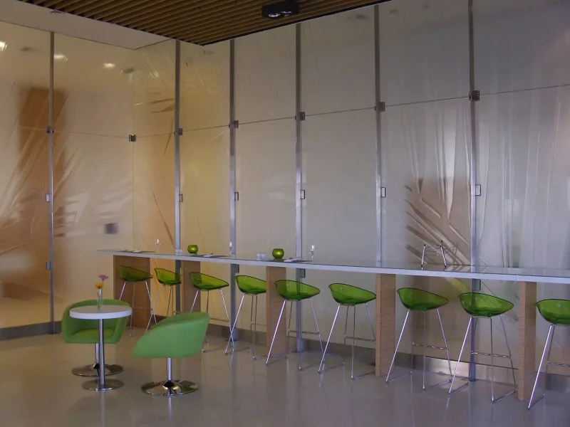 Leaf-pattern textured glass partition behind a long bar counter in a restaurant