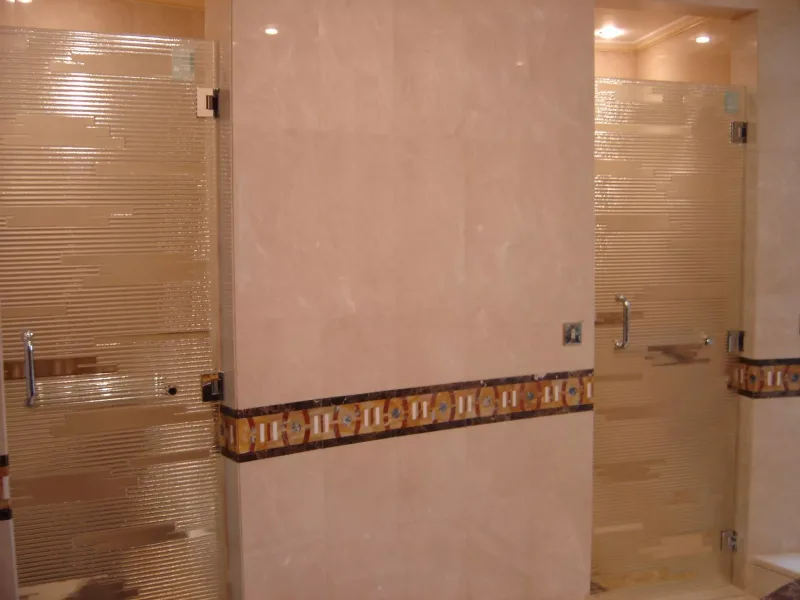 Pair of hinged reeded glass shower doors with banded pattern in a marble bathroom
