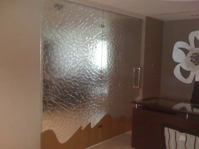 Frameless textured glass door and partition with wave-shaped base beside a reception desk