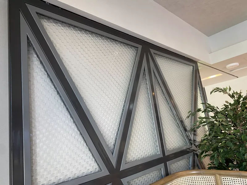Triangular dark steel frames with woven-texture glass panels forming a feature wall