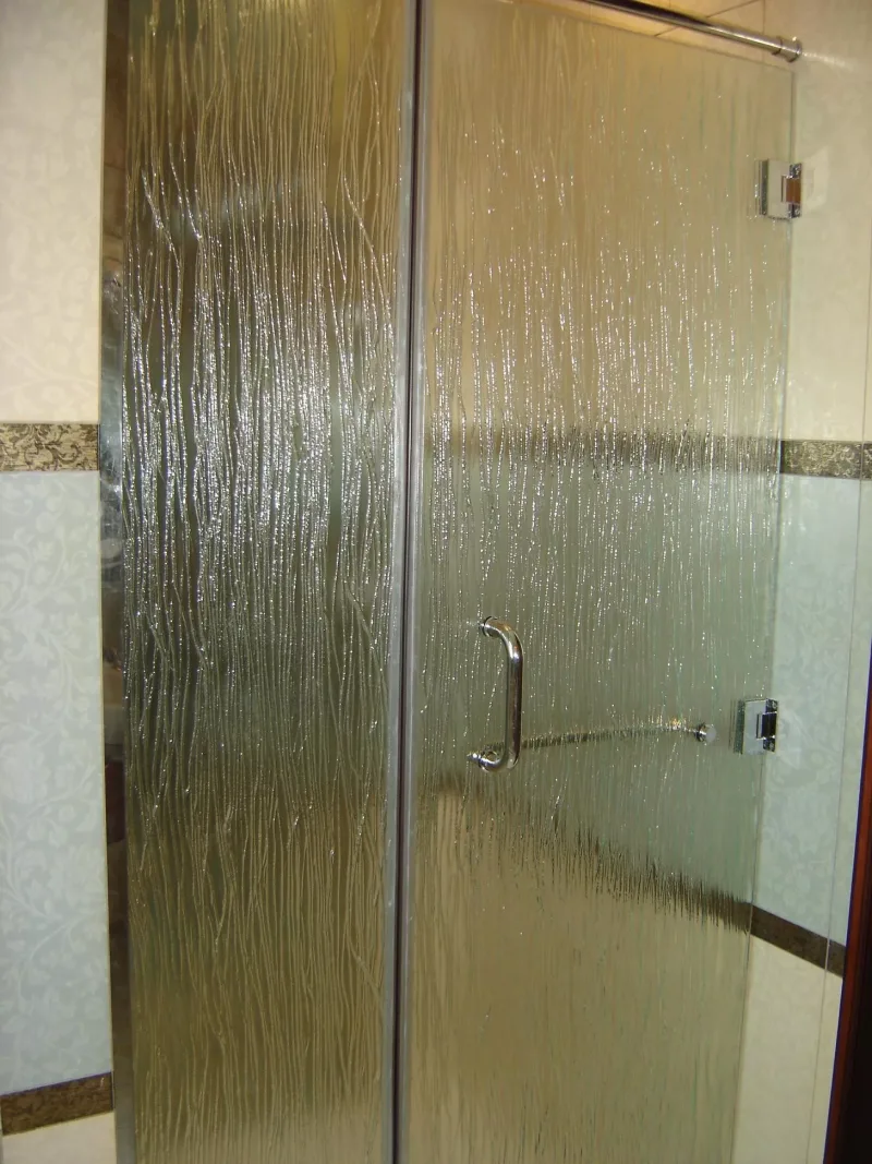 Hinged shower door and fixed panel in vertical-line textured glass with chrome handle